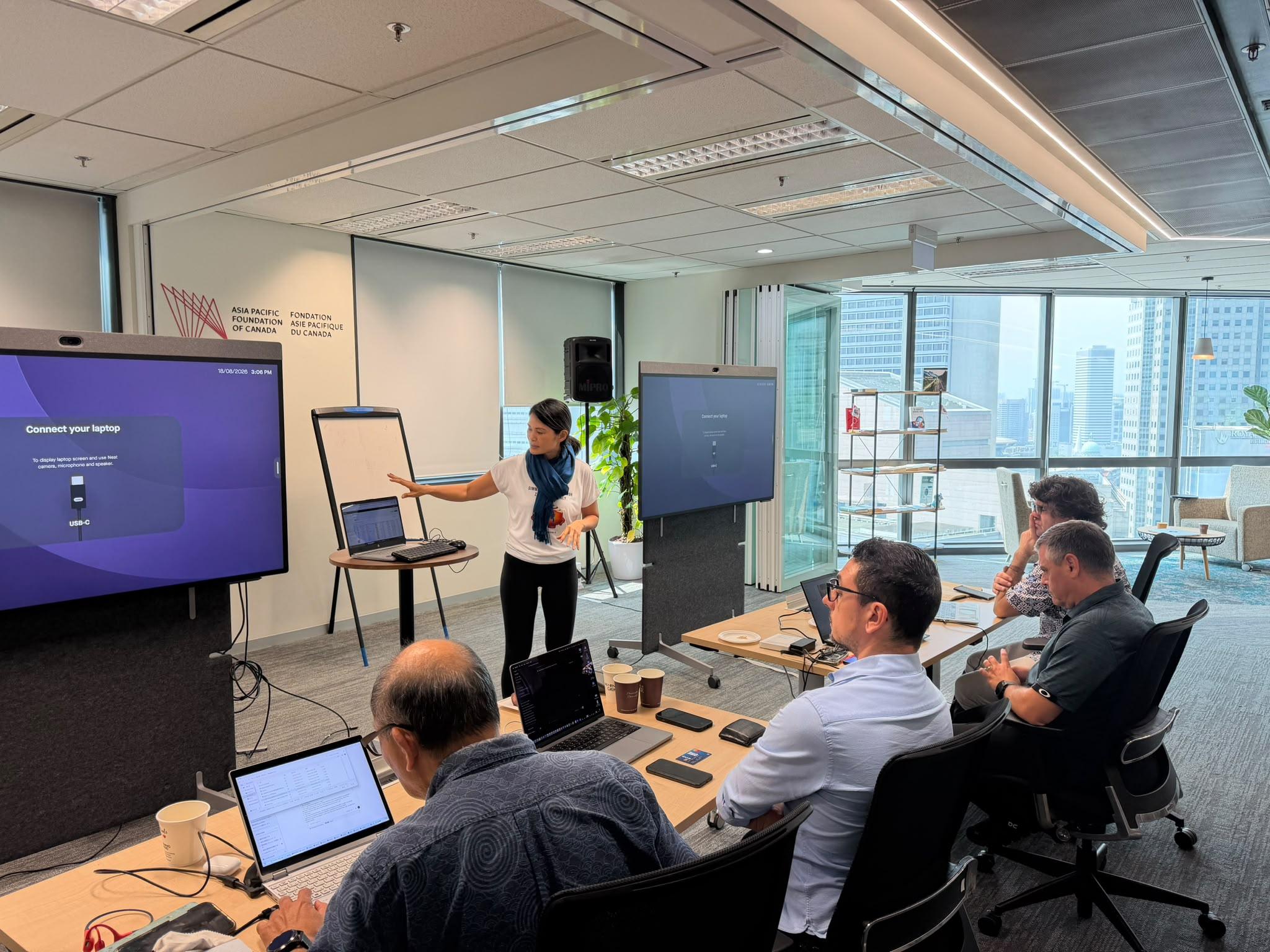 A woman from the first AI Upgrade cohort presenting her build to the group in Singapore